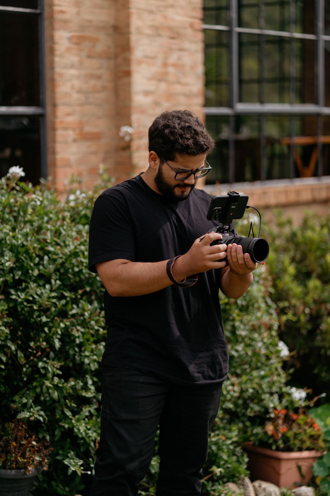 Luiz Oliveira filmando com câmera em um jardim